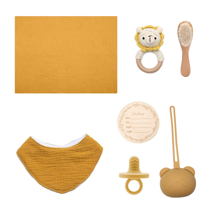 Sea Dragon Dreams baby gift set with mustard muslin bib, wooden brush, lion rattle, pacifier, and milestone card.