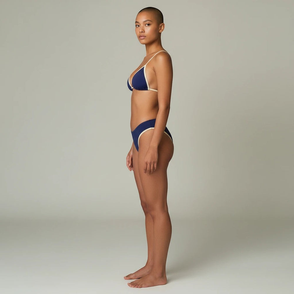 Sea Dragon Dreams navy blue bikini set with contrast trim worn by a model in a side profile view.