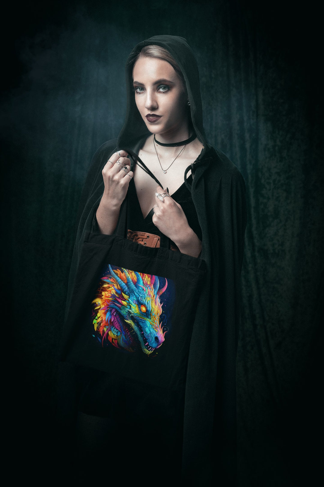 Sea Dragon Dreams black cotton canvas tote bag featuring a vibrant neon dragon print, held by a woman in a dark hood.