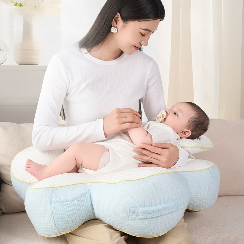 Sea Dragon Dreams nursing pillow in light blue and white, supporting a mother and baby during breastfeeding on a sofa.