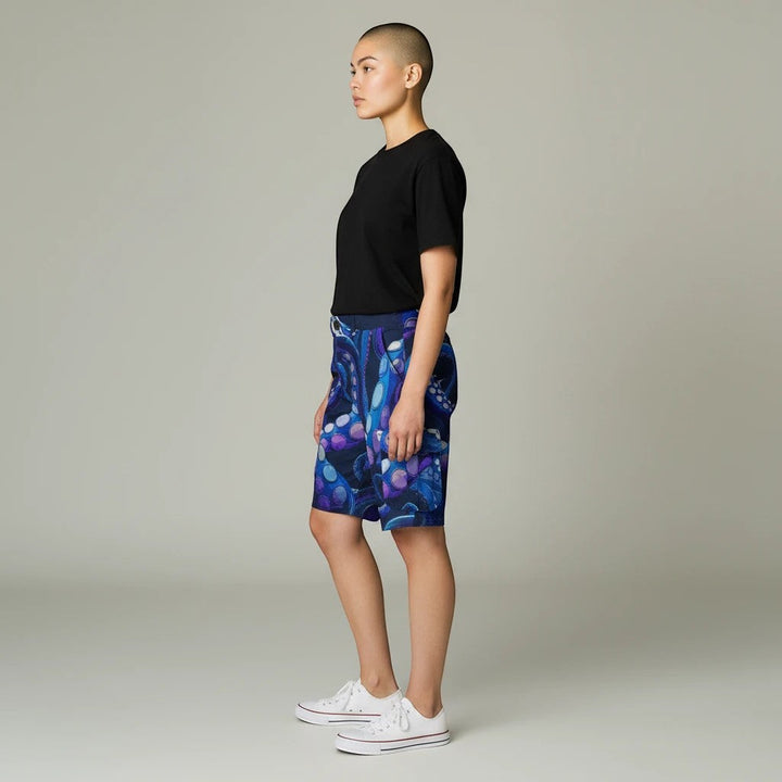 Sea Dragon Dreams cargo shorts with a blue octopus tentacle pattern, worn by a model in a side profile view.
