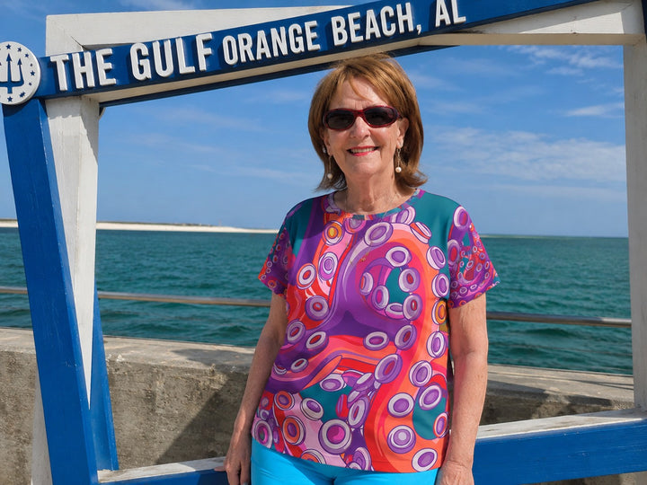 A woman wearing a Sea Dragon Dreams Color Me Octopus sports jersey with a vibrant purple and orange octopus print.