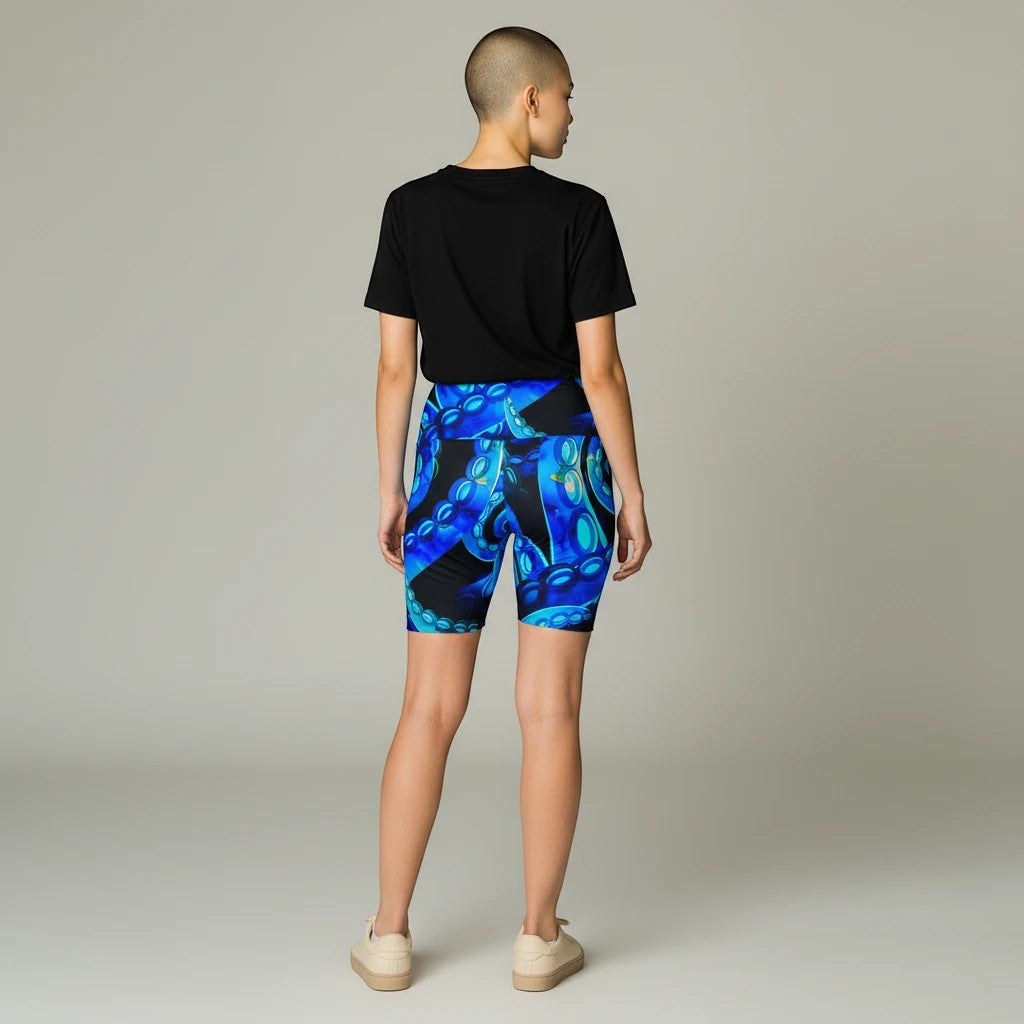 Model wearing Sea Dragon Dreams Octopus Delight workout shorts with a vibrant blue octopus tentacle print.