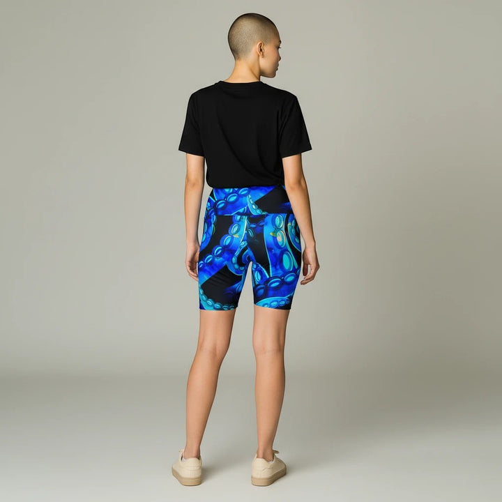 Model wearing Sea Dragon Dreams Octopus Delight workout shorts with a vibrant blue octopus tentacle print.