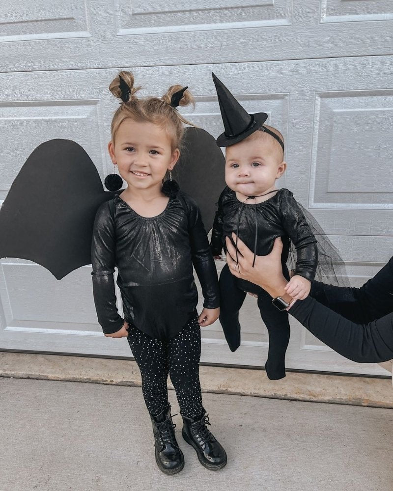 Two girls wearing Sea Dragon Dreams onyx shimmer long sleeve leotards styled as bat and witch Halloween costumes.