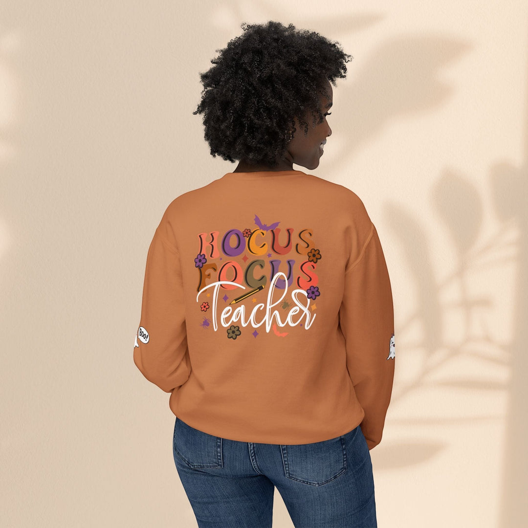 Sea Dragon Dreams unisex orange crewneck sweatshirt with Hocus Focus Teacher graphic on back, worn by a woman.