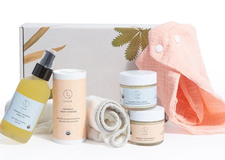 Sea Dragon Dreams organic baby gift set with skincare balms, baby oil, powder, and a soft pink burping cloth in a box.