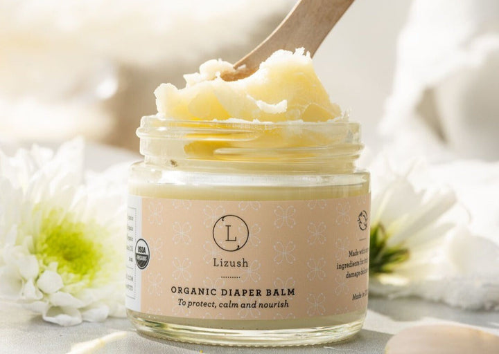 Sea Dragon Dreams organic diaper balm in a glass jar with a wooden scoop, featuring natural ingredients for baby skin.