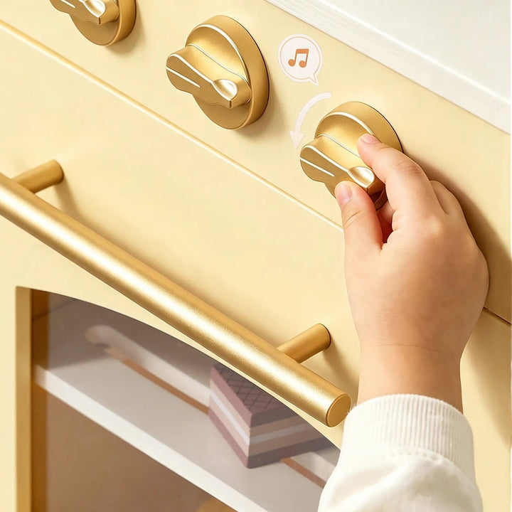Sea Dragon Dreams Tiny Land wooden play kitchen in pale yellow with gold knobs and handle being turned by a child