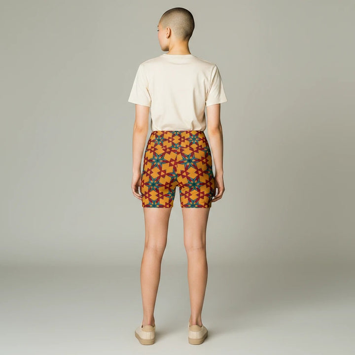 Model wearing Sea Dragon Dreams red and yellow patterned polyester workout shorts with a plain beige t-shirt