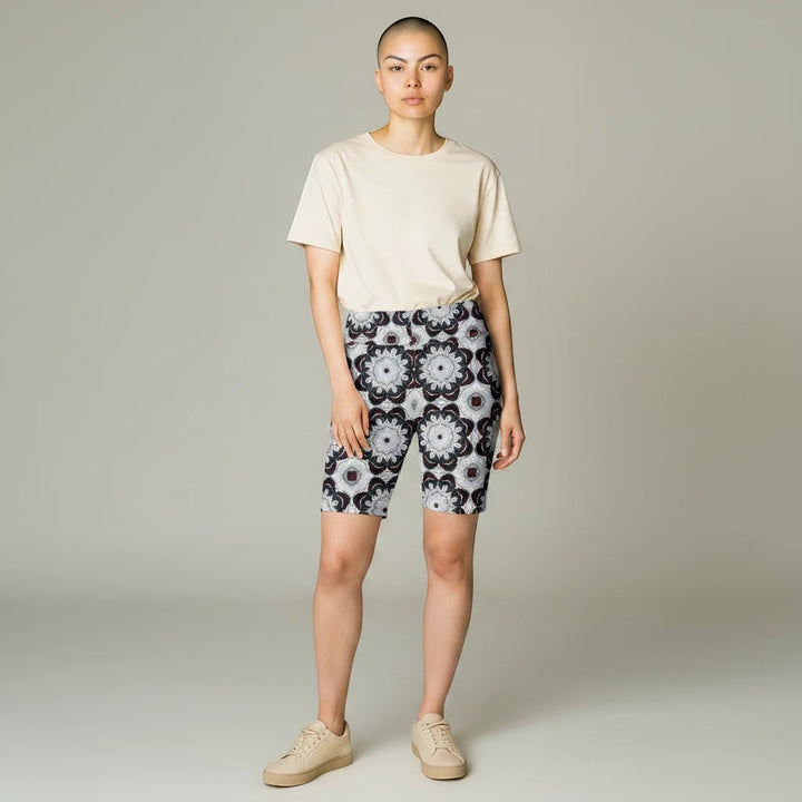 Model wearing Sea Dragon Dreams black and white patterned workout shorts with a beige t-shirt and sneakers.