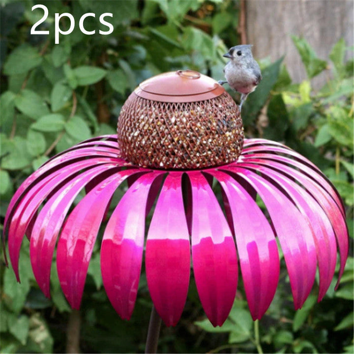 Sea Dragon Dreams petal-shaped metal bird feeder in vibrant pink with a central seed container in a garden setting