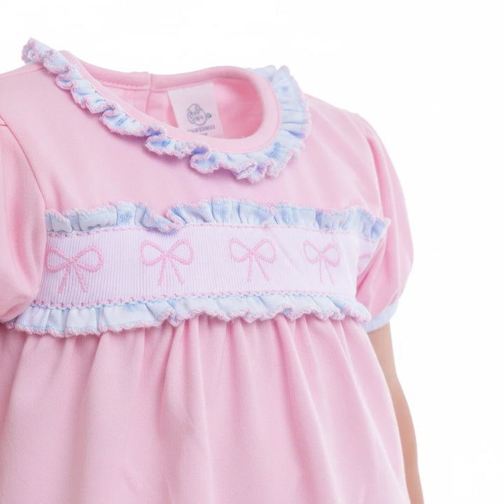 Sea Dragon Dreams pink baby dress with puff sleeves, ruffle trim, and a chest band featuring embroidered bow details.