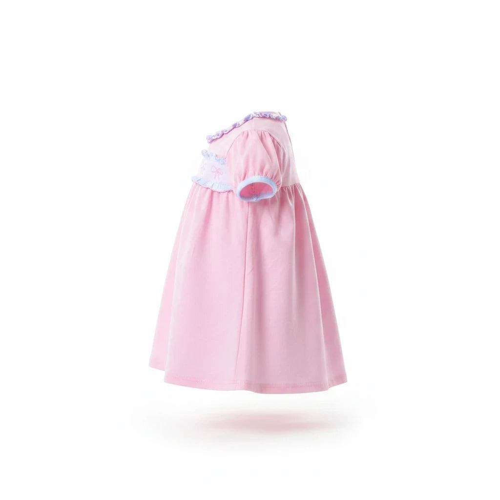Sea Dragon Dreams pink baby dress with puff sleeves, ruffle trim, and bow chest detail, side view.