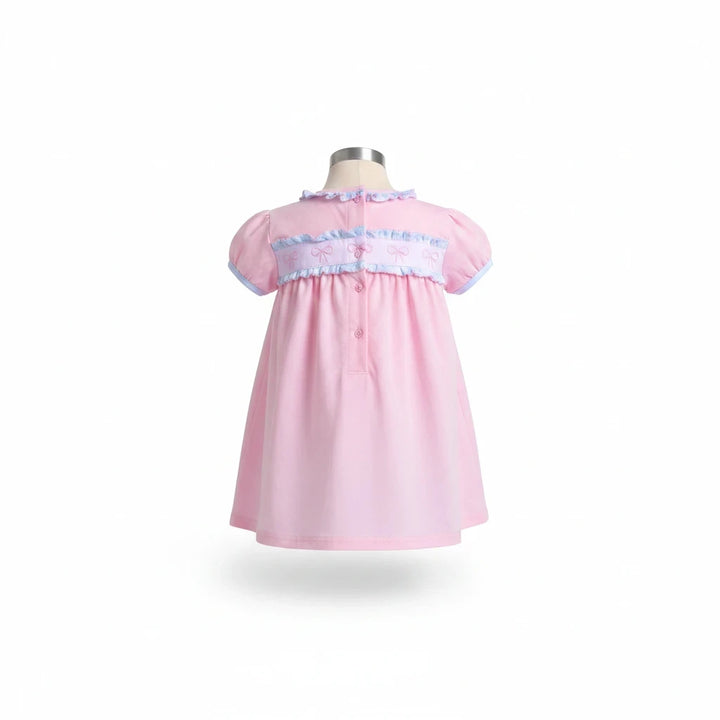 Sea Dragon Dreams pink baby dress with puff sleeves, ruffle trim, and bow detail on the back, shown on a mannequin.
