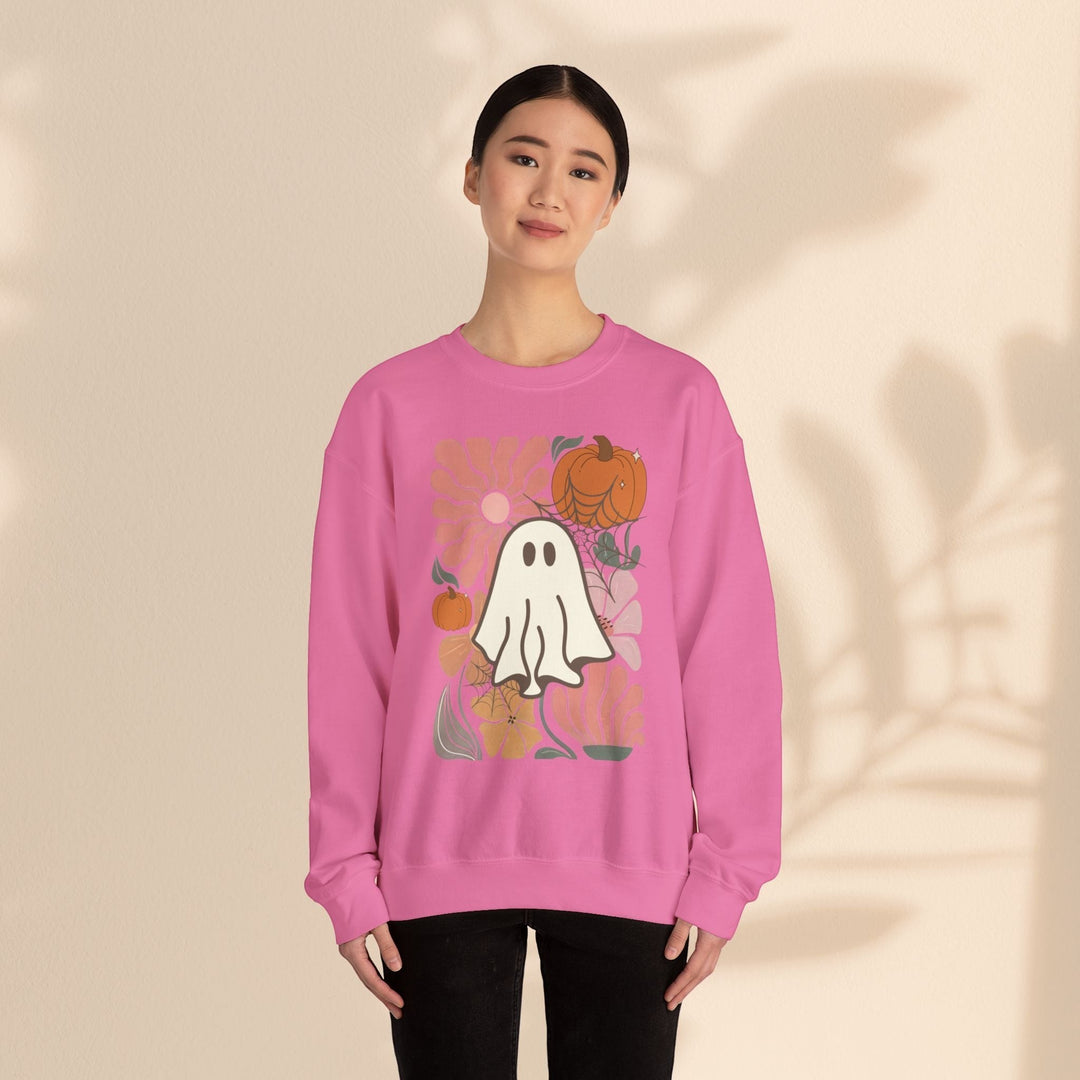 A woman wearing a Sea Dragon Dreams pink crewneck sweatshirt featuring a cute ghost, pumpkin, and floral graphic.