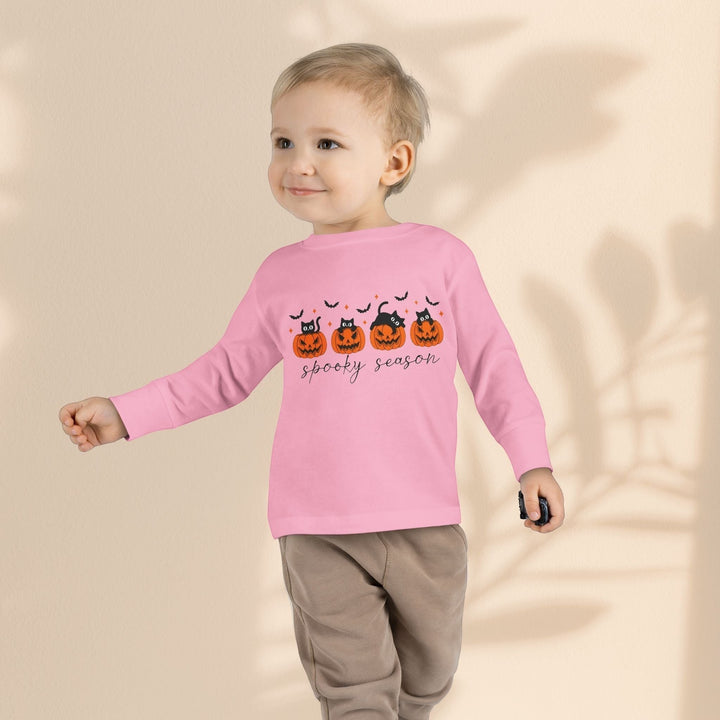 Toddler wearing a Sea Dragon Dreams pink long sleeve tee with a spooky pumpkin and black cat Halloween graphic