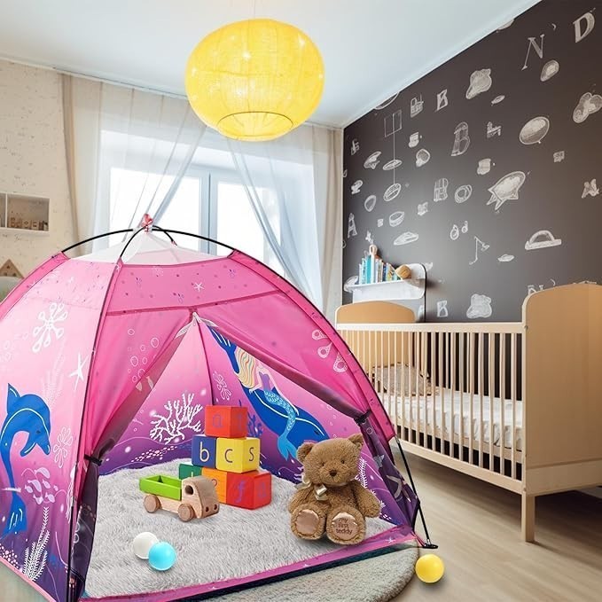 Sea Dragon Dreams pink mermaid pop-up play tent set up in a cozy child's bedroom with toys and a wooden crib.