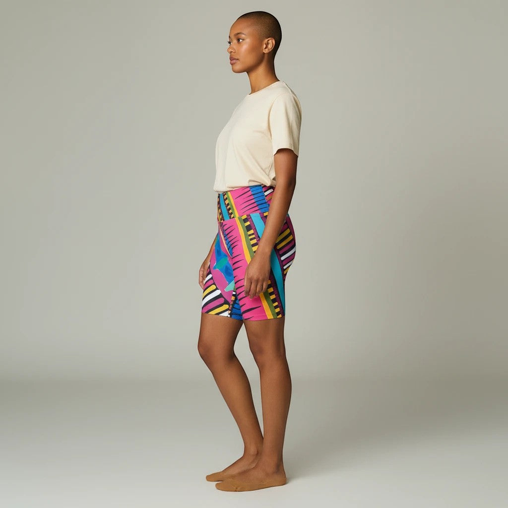 Model wearing Sea Dragon Dreams Pink Party workout shorts with a vibrant geometric pattern and mid-rise waistband.