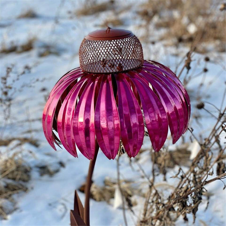 Sea Dragon Dreams petal-shaped metal bird feeder in vibrant pink, featuring a mesh seed container in a snowy garden.