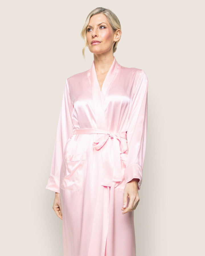 A woman wearing a Sea Dragon Dreams long pink silk robe with a waist tie and long sleeves against a neutral background.
