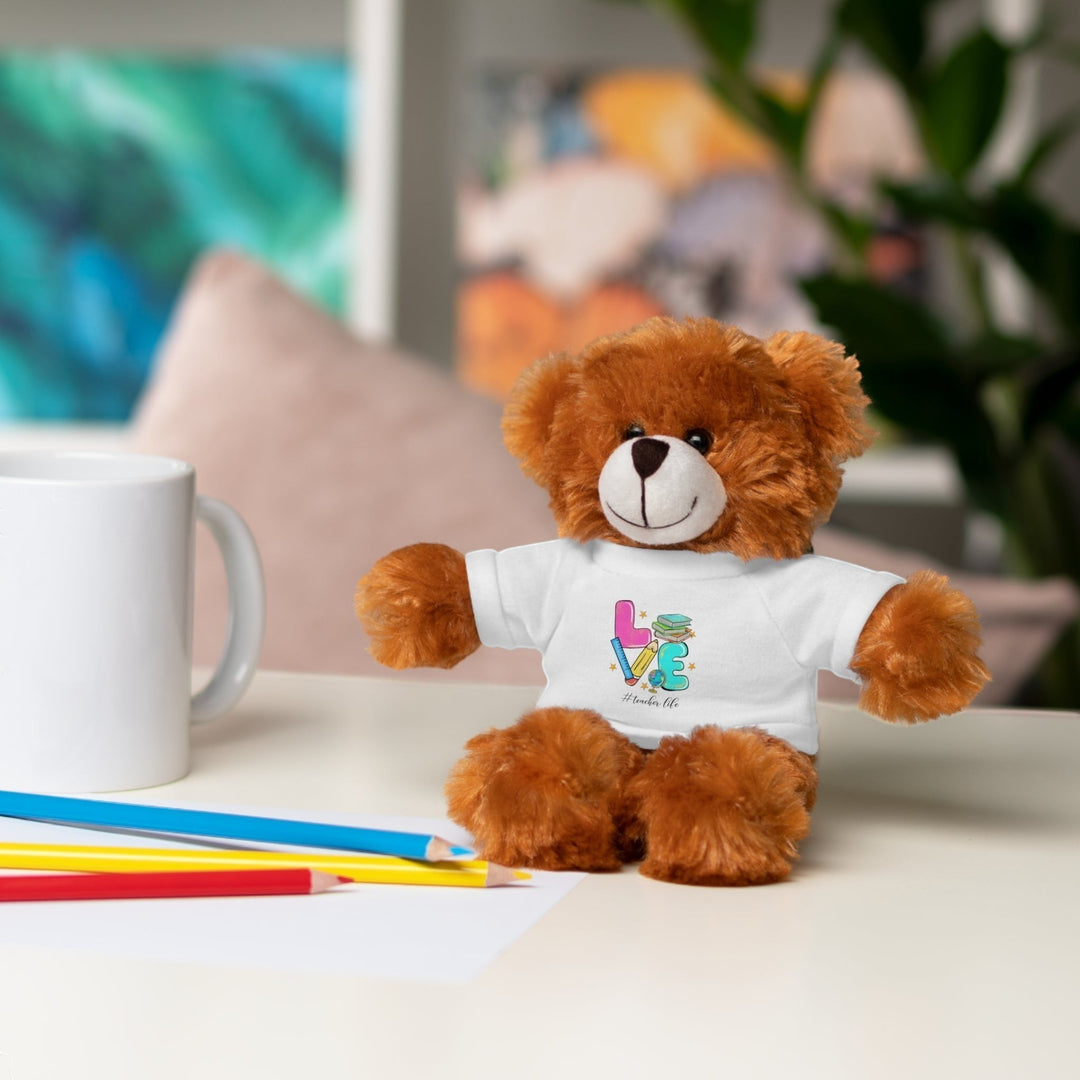 Sea Dragon Dreams brown plush teddy bear wearing a white cotton t-shirt with Love Teacher Life graphic on a desk