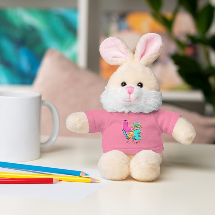 Sea Dragon Dreams plush bunny stuffed animal wearing a pink t-shirt with Love Teacher Life graphic on a desk
