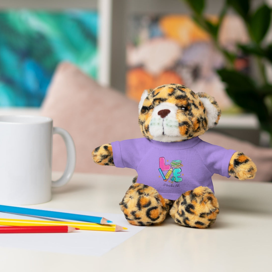 Sea Dragon Dreams plush jaguar stuffed animal wearing a purple t-shirt with Love Teacher Life graphic on a desk