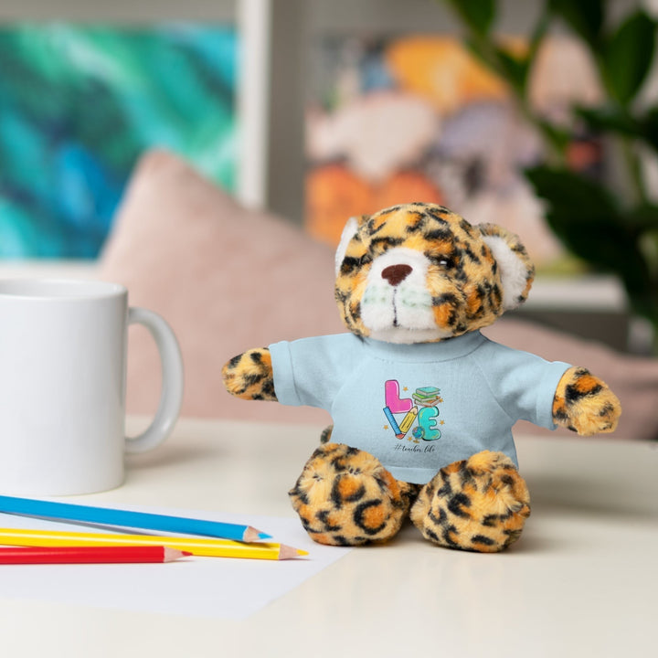 Sea Dragon Dreams plush jaguar stuffed animal wearing a light blue t-shirt with Love Teacher Life graphic on a desk.