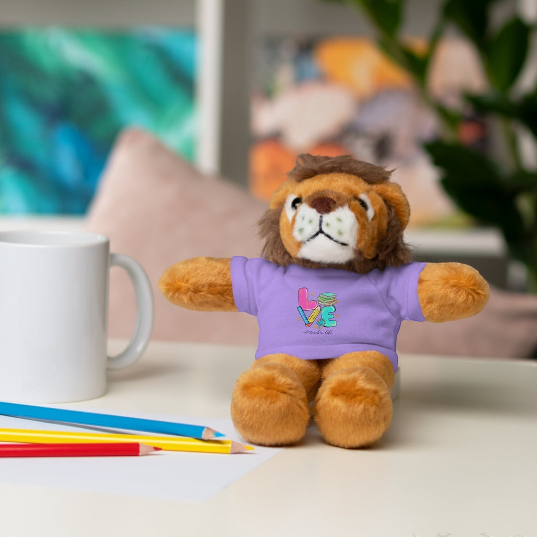 Sea Dragon Dreams plush lion stuffed animal wearing a purple t-shirt with Love Teacher Life text on a desk
