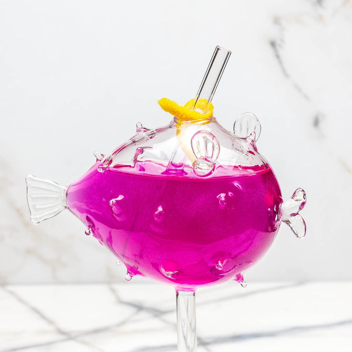 Sea Dragon Dreams BarConic puffer fish cocktail glass filled with a vibrant pink drink and a clear reusable straw.