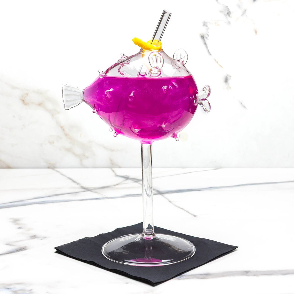 Sea Dragon Dreams BarConic puffer fish cocktail glass filled with a vibrant purple drink and a reusable straw.