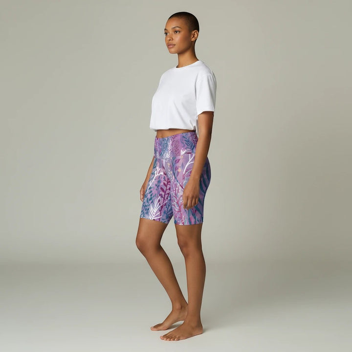 Model wearing Sea Dragon Dreams purple seaweed print polyester workout shorts with a white crop top, side view.