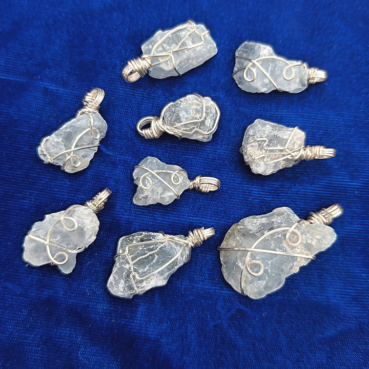 Sea Dragon Dreams handmade raw celestite crystal pendants with silver-plated wire wrapping on a blue velvet background.