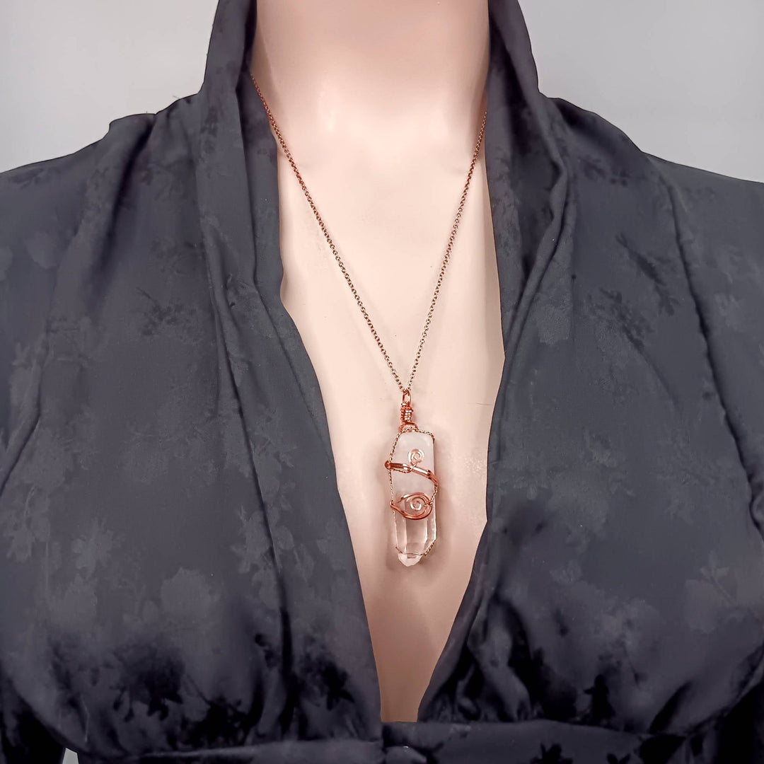 Sea Dragon Dreams raw clear quartz crystal point pendant wire-wrapped in copper on a mannequin wearing a black top.