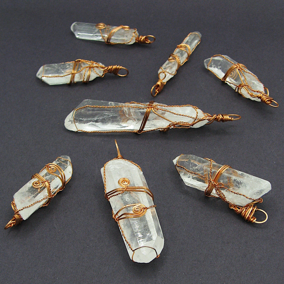 Sea Dragon Dreams raw quartz crystal pendants wrapped in rustic copper wire, displayed on a dark background.