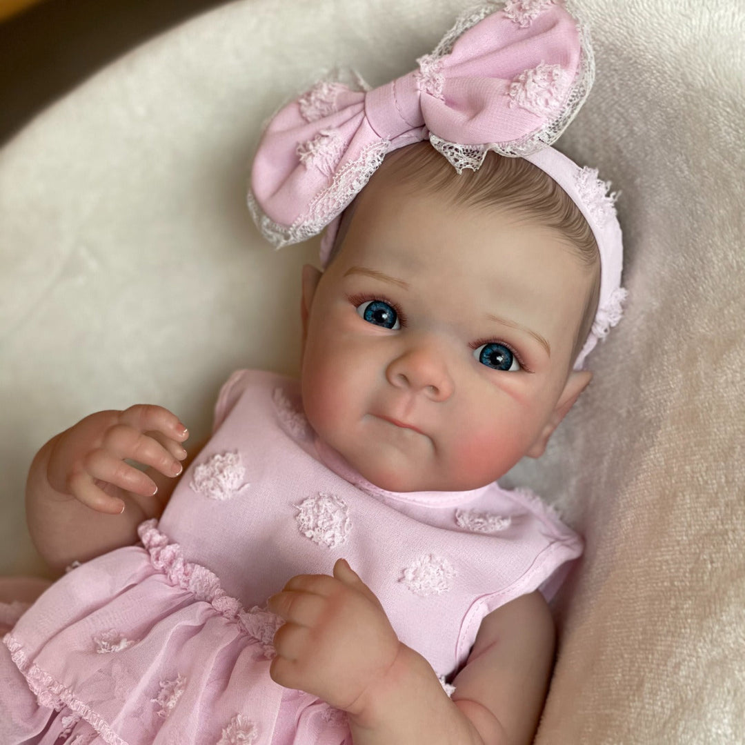 Sea Dragon Dreams 18-inch lifelike reborn baby doll with blue eyes, wearing a pink dress and matching bow headband.