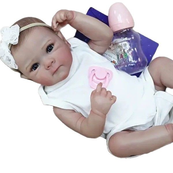 Sea Dragon Dreams 18-inch lifelike reborn baby doll in a white outfit with a pink pacifier and baby bottle.
