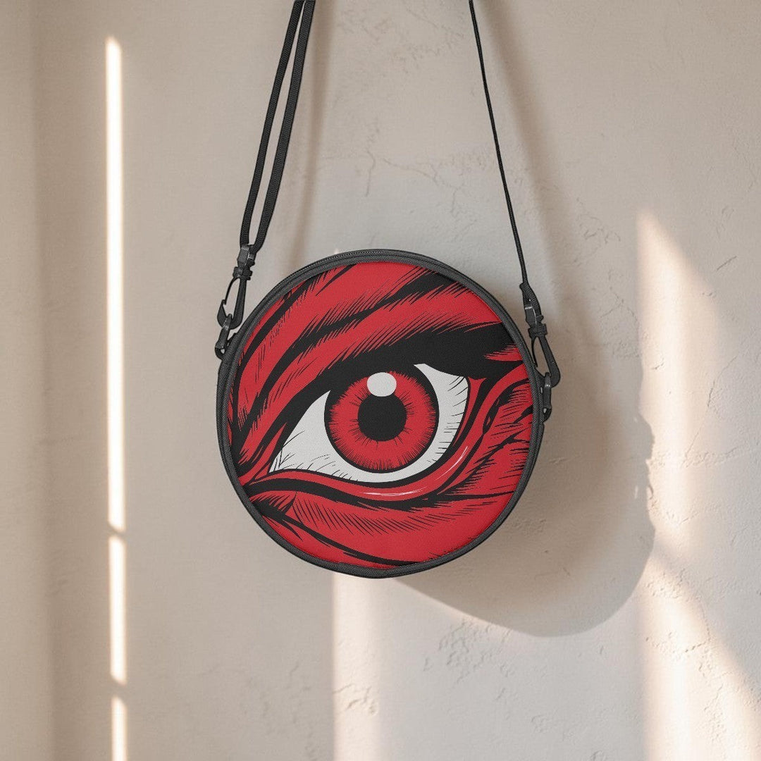 Sea Dragon Dreams round canvas satchel bag featuring a dramatic red eye illustration and adjustable black strap.