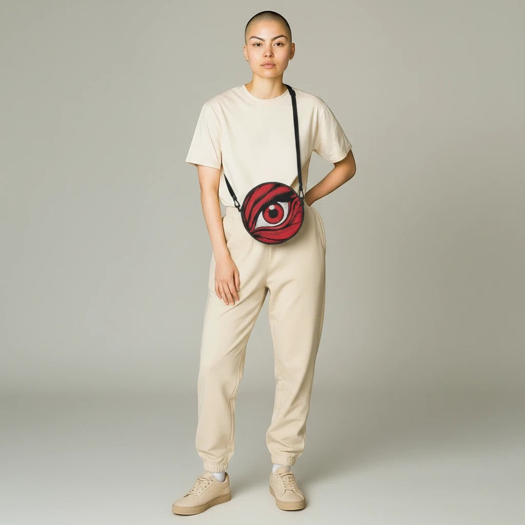 Sea Dragon Dreams round canvas satchel bag with red eye graphic, worn crossbody by a model in beige loungewear.