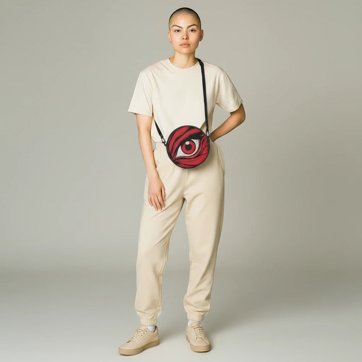 Sea Dragon Dreams round canvas satchel bag with red eye graphic, worn crossbody by a model in beige loungewear.