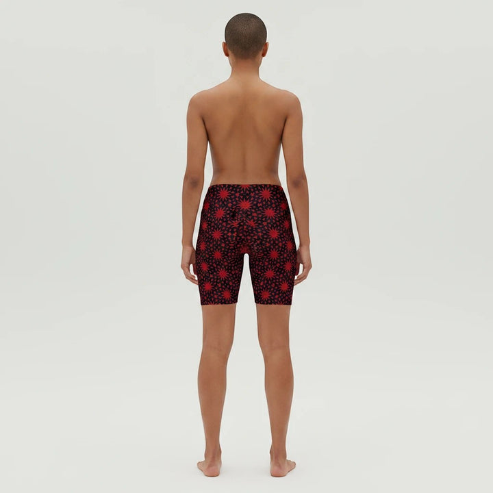 Model wearing Sea Dragon Dreams red workout shorts with a black and red spiral star pattern, back view.