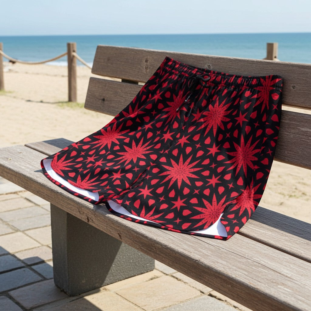 Sea Dragon Dreams men's polyester shorts with a bold red star pattern on a black background, displayed on a beach bench.