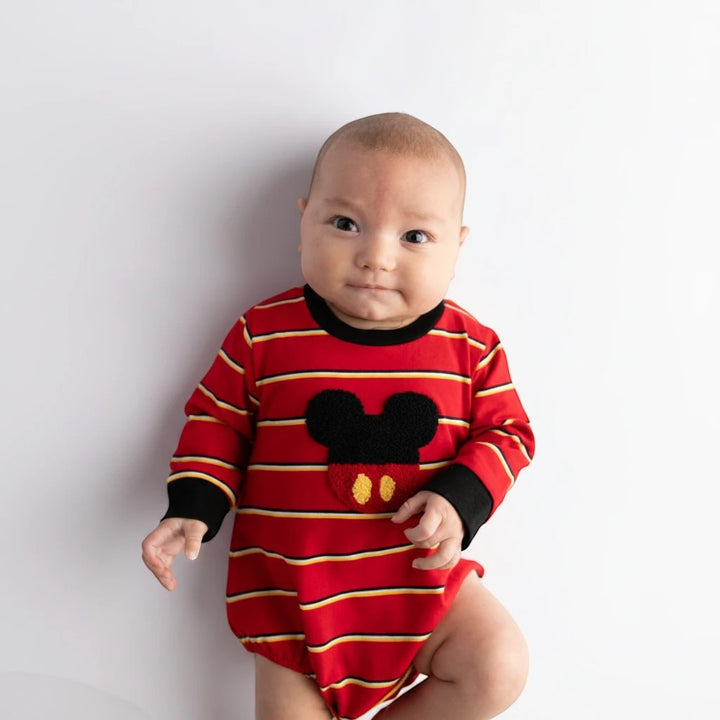 Baby wearing a Sea Dragon Dreams red striped long-sleeve bubble romper with a mouse-inspired applique on white background