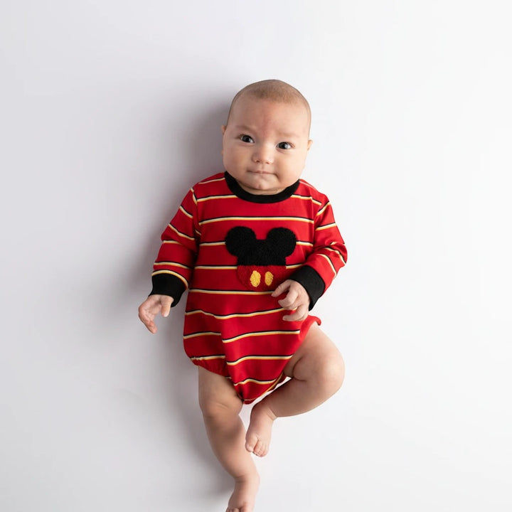 Baby wearing a Sea Dragon Dreams red striped long-sleeve bubble romper with a mouse-inspired applique on white background