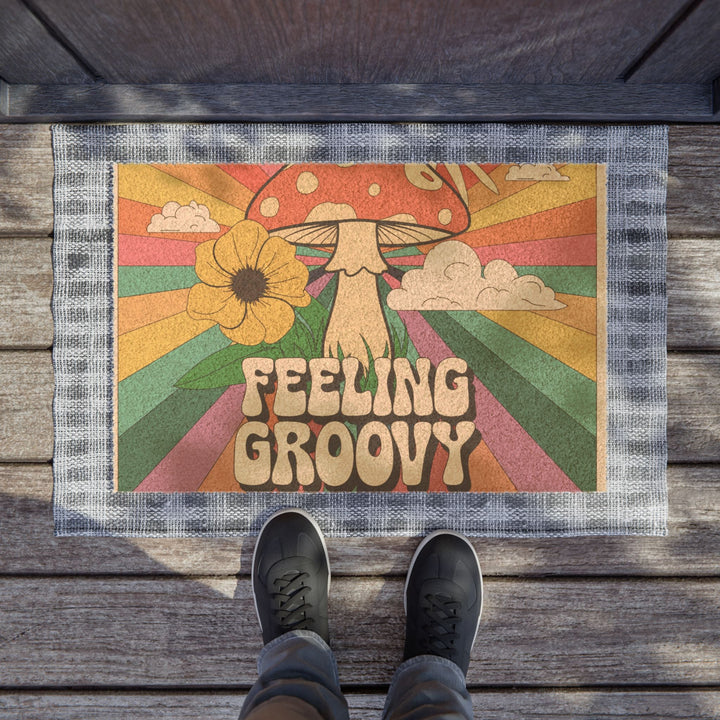 Sea Dragon Dreams Feeling Groovy door mat with retro mushroom, flower, and sunburst design on a wooden porch