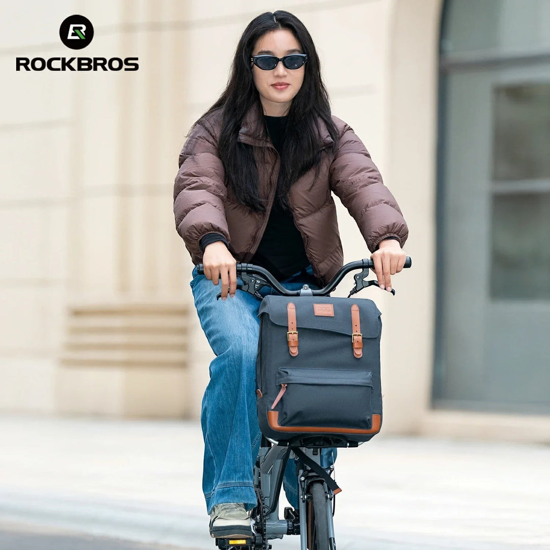 Sea Dragon Dreams ROCKBROS vintage blue cotton cycling backpack mounted on a folding bike, worn by a woman in a brown jacket.