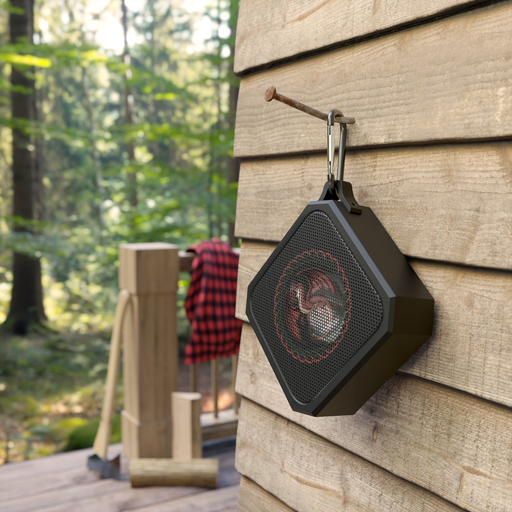 Sea Dragon Dreams rugged portable Bluetooth speaker with dragon emblem hanging on a wooden wall in a forest setting.