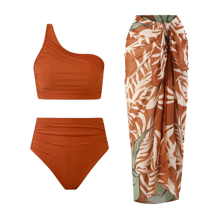 Sea Dragon Dreams rust orange one-shoulder bikini set with high-waisted bottoms and a matching tropical print sarong.
