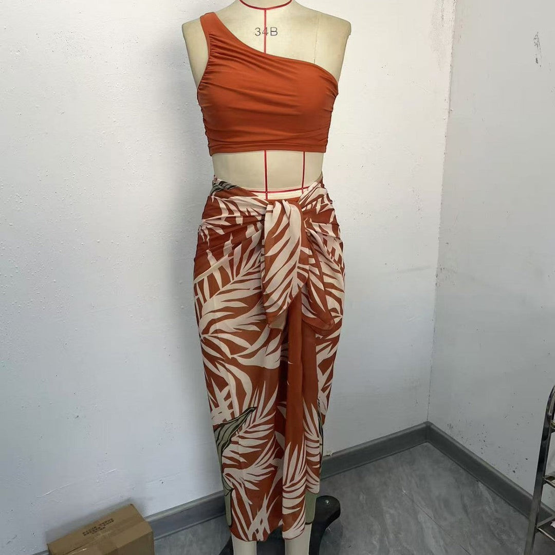 Sea Dragon Dreams rust orange one-shoulder bikini top paired with a matching tropical leaf print sarong on a mannequin